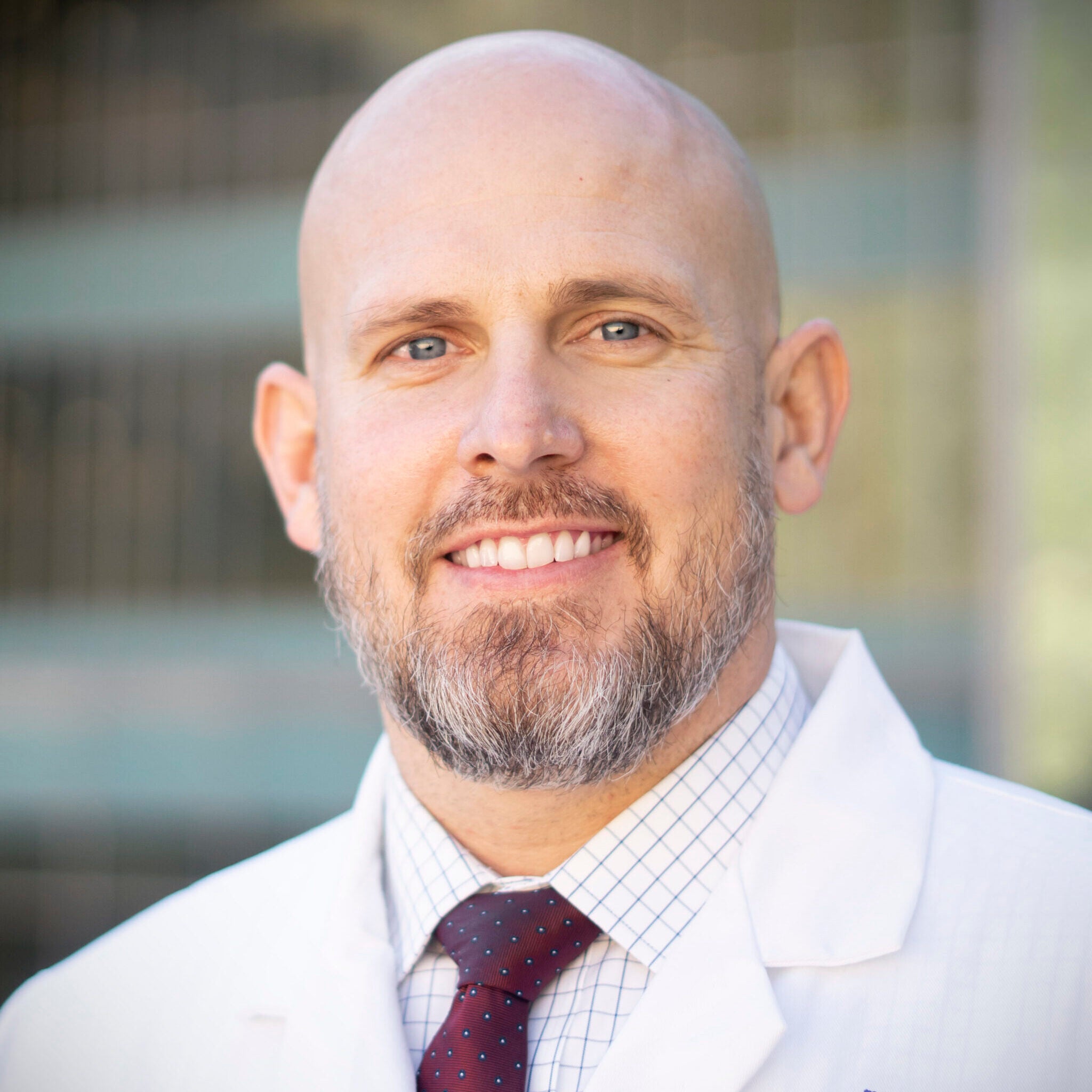 Headshot of Skyler Johnson. He is wearing a medical coat and tie