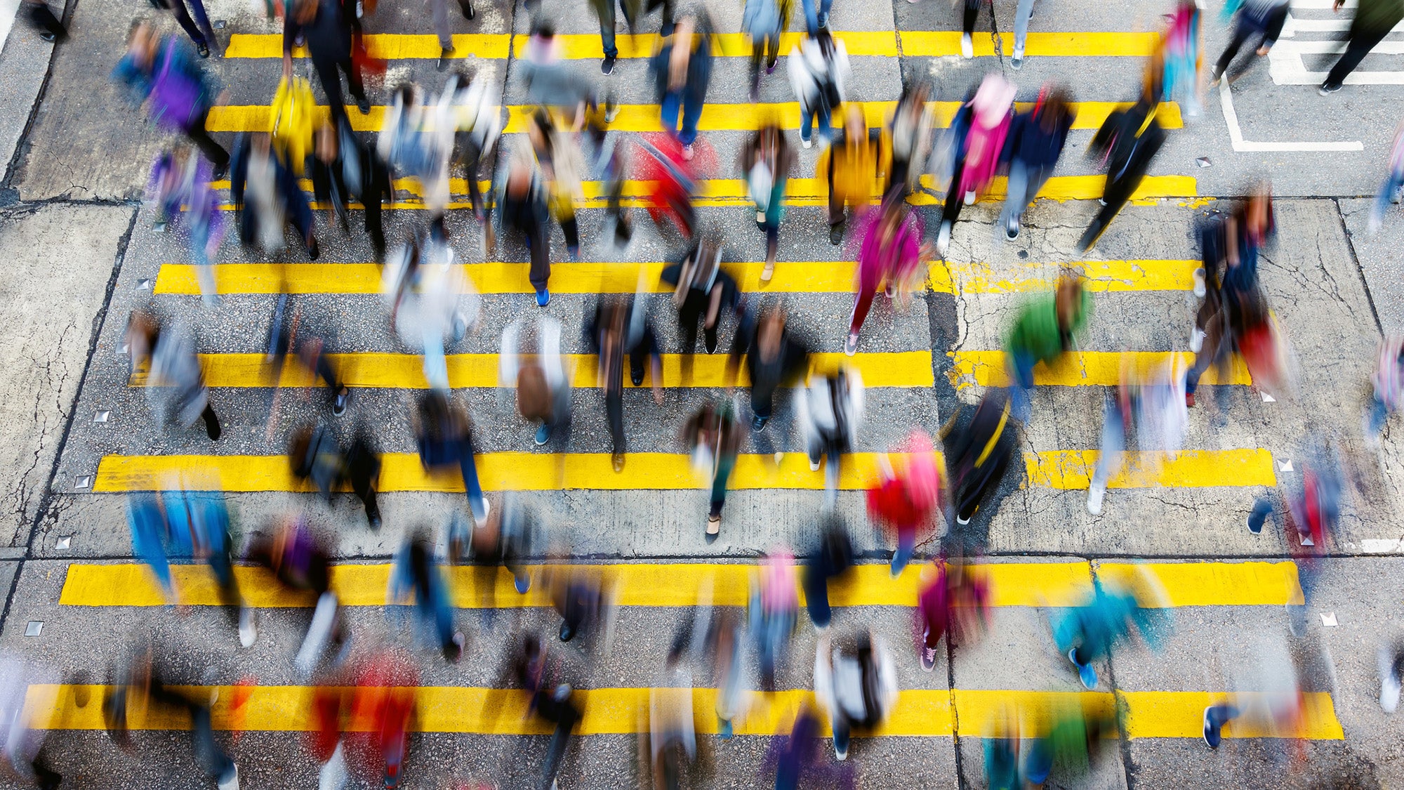 Blurred image of crowd of people crossing city street.