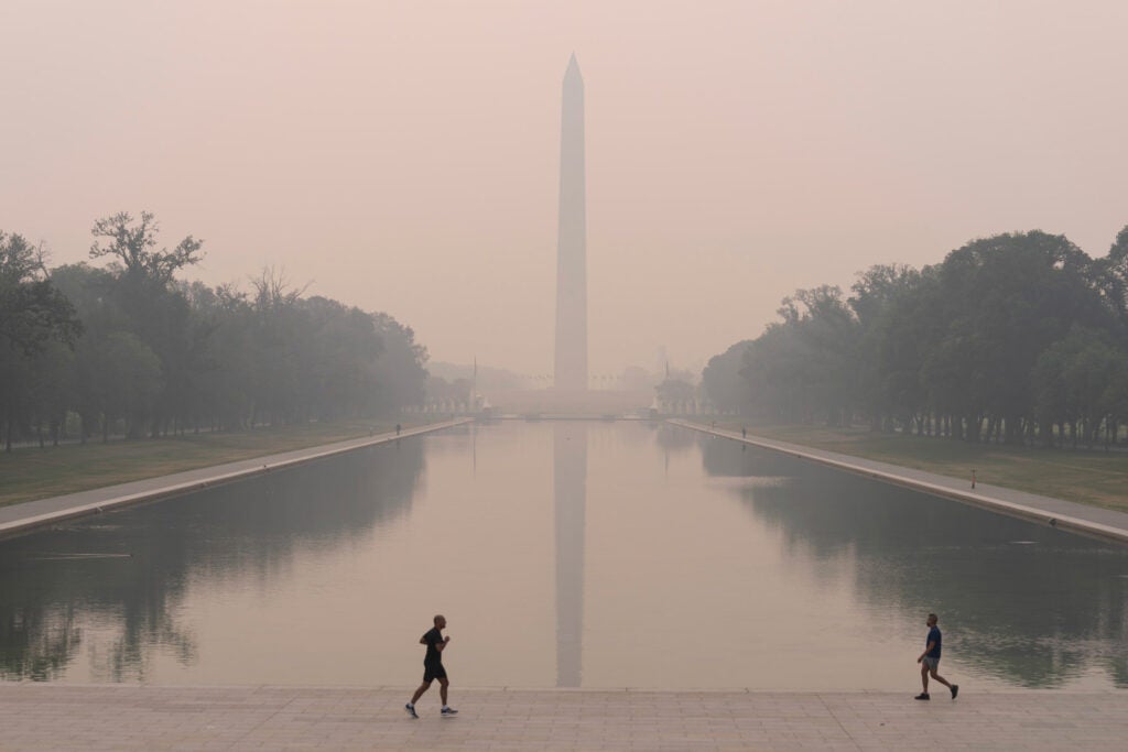 With the Washington Monument in the background and with a thick layer of smoke people run at the National Mall, June 8, 2023, in Washington. 