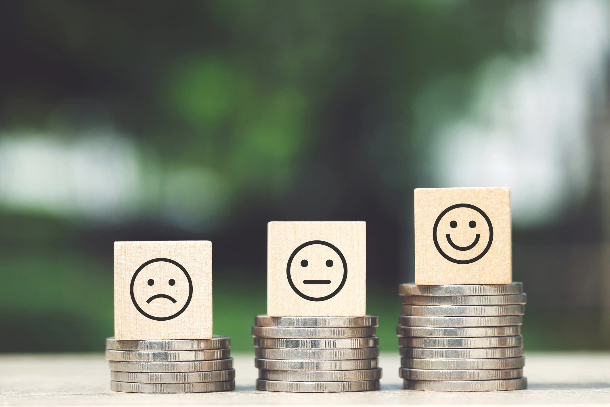 Stacks of three quarters lined up in ascending height. The shortest stack of quarters has a block with a sad face on it; the medium stack has a block with a neutral face on it; the tallest stack, a happy face.