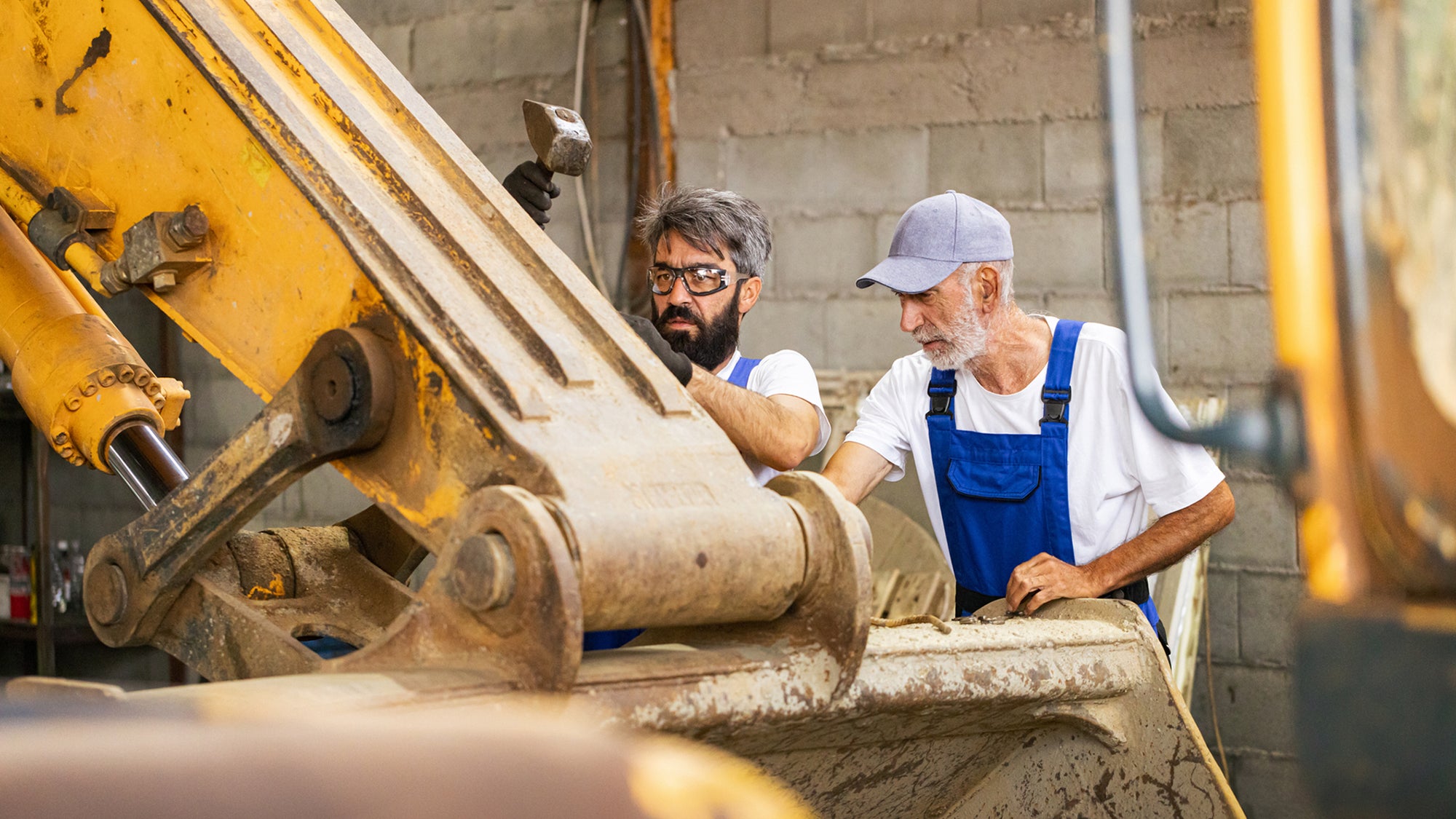 Two men are repairing an excavator.