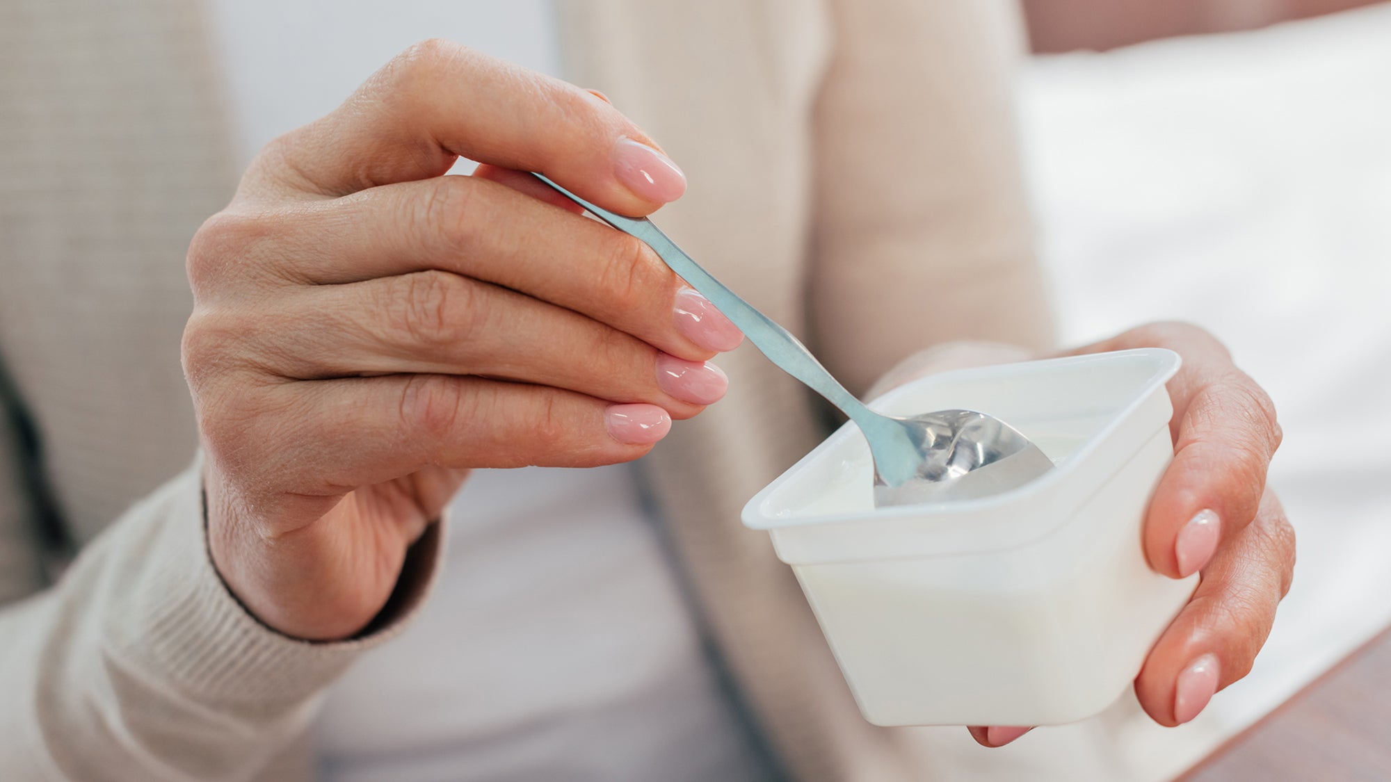 close-up partial view of senior woman eating yogurt