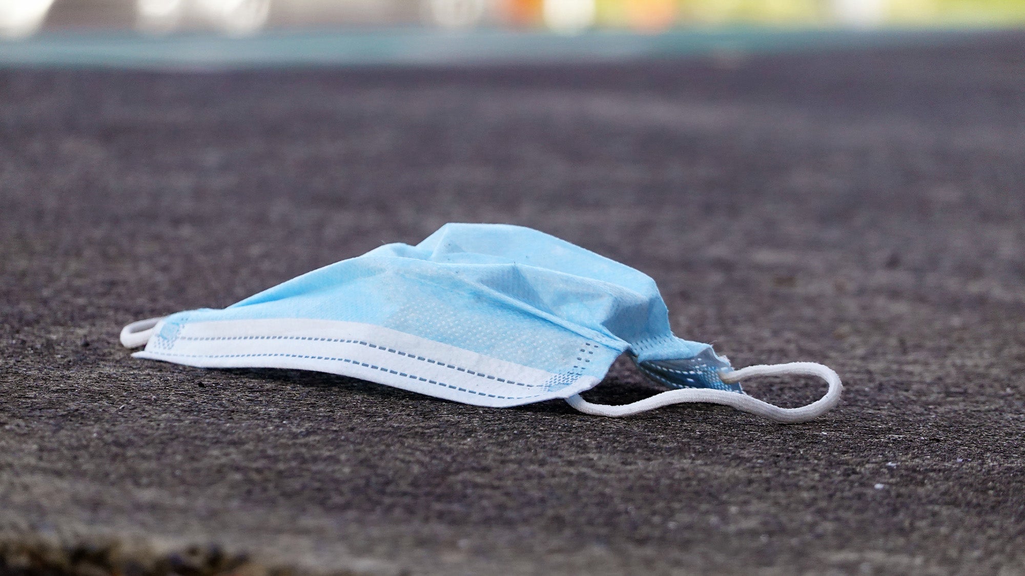 Discarded medical face mask on street pavement.