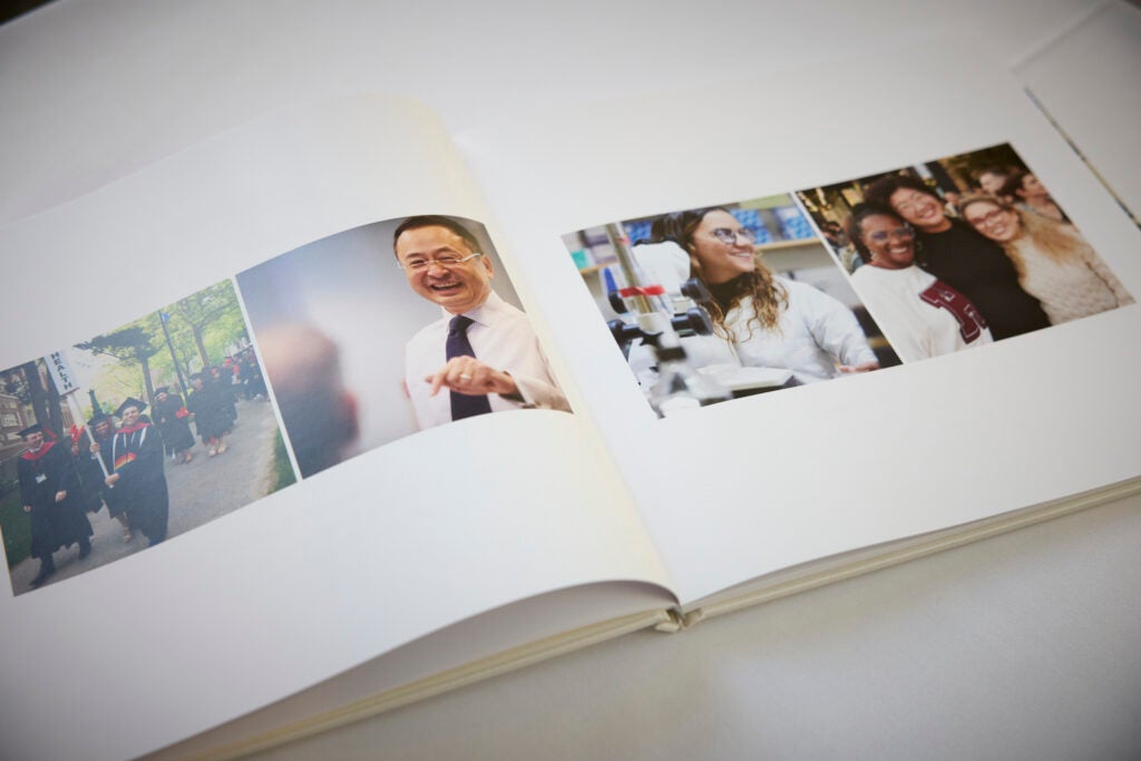 An open book shows images of joyful scenes on campus, including commencement, a classroom, and a lab. 
