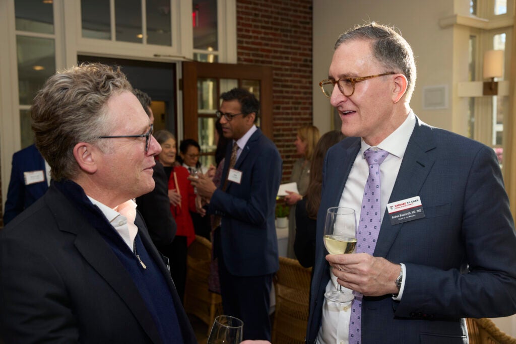 Holding a wine glass, Dean Ciccarelli converses with a guest. 