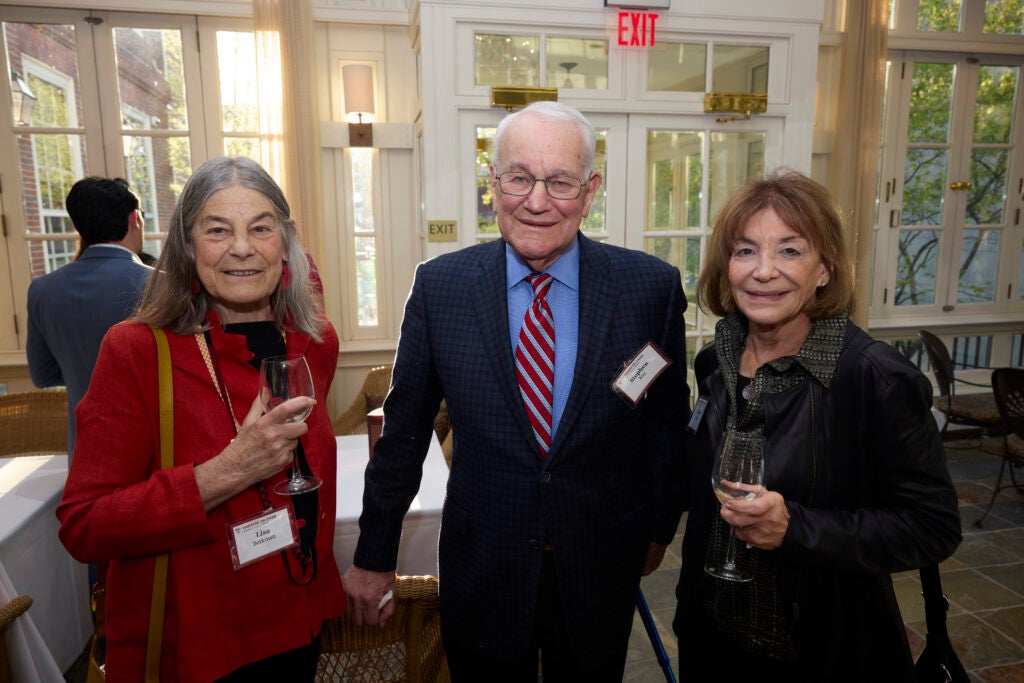 Three guests pose together, with the ladies on either side holding glasses. 