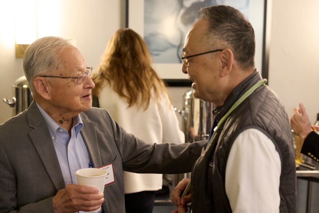 A guest is greeting Gerald Chan, with a hand on his shoulder. 