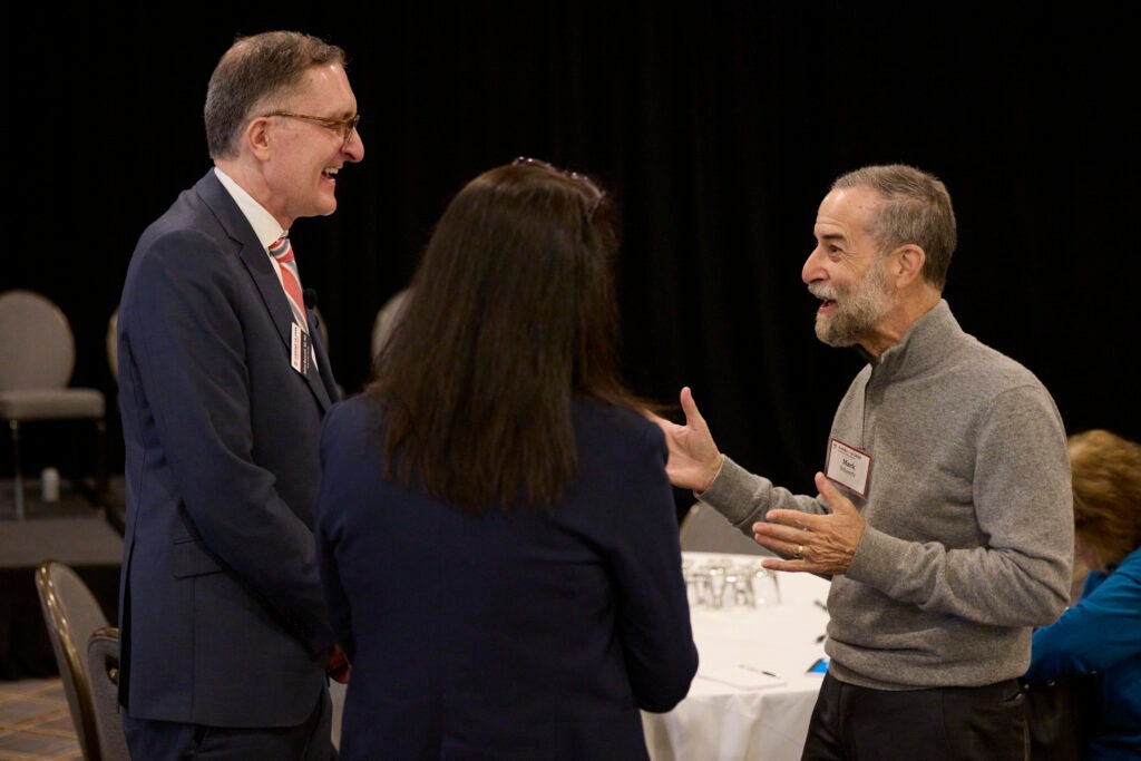 The Dean smiles in conversation with two guests. 
