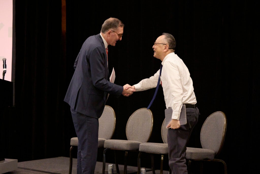 The Dean and Gerald Chan, both smiling, shake hands on stage
