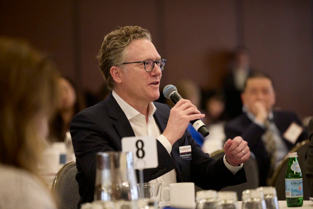A man with glasses, seated at table 8, asks a question.