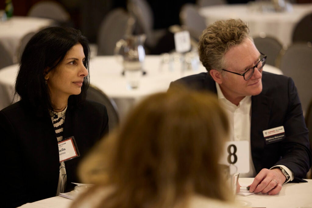 Two guests closely watch a speaker out of frame to their left. 