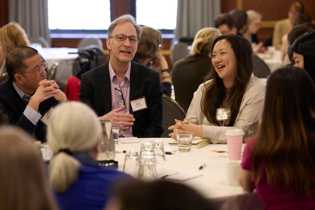 A woman smiles as one of her tablemates is speaking. 