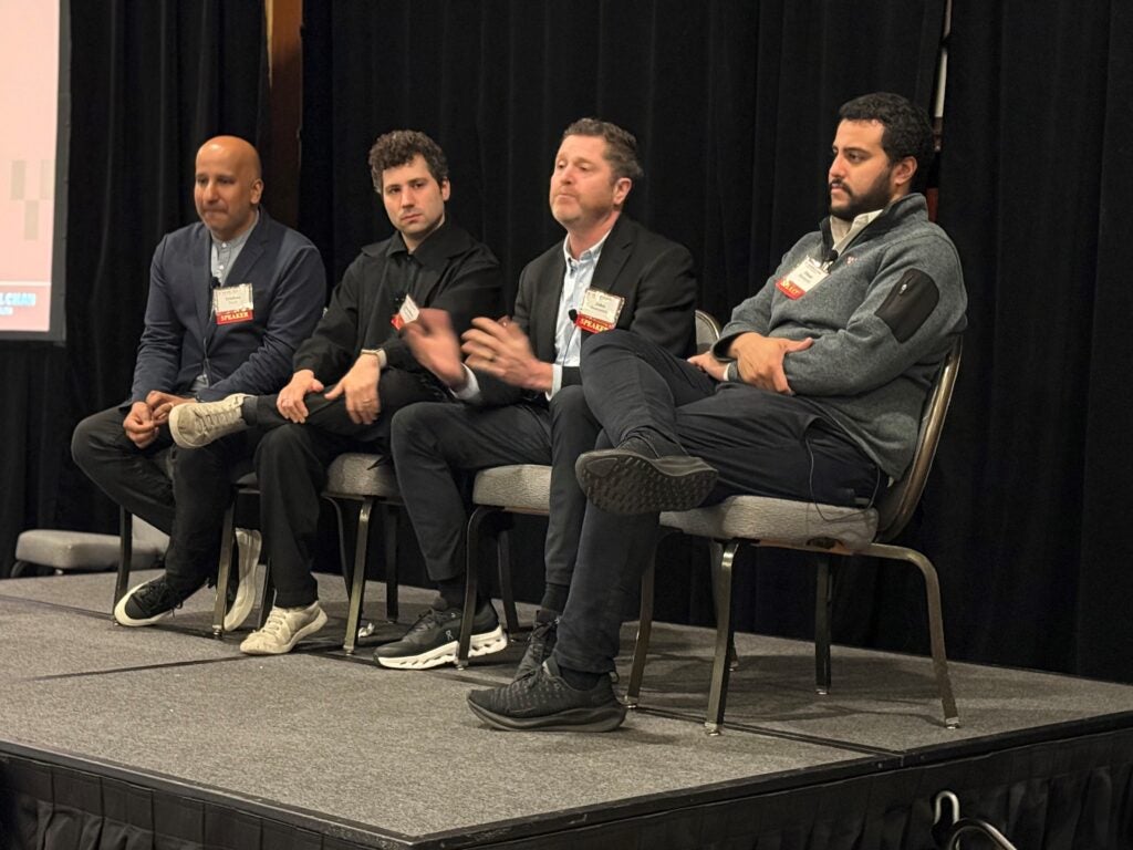 The four participants are seated, with moderator Trishan at left. John Brownstein, seated second from left, is speaking. 