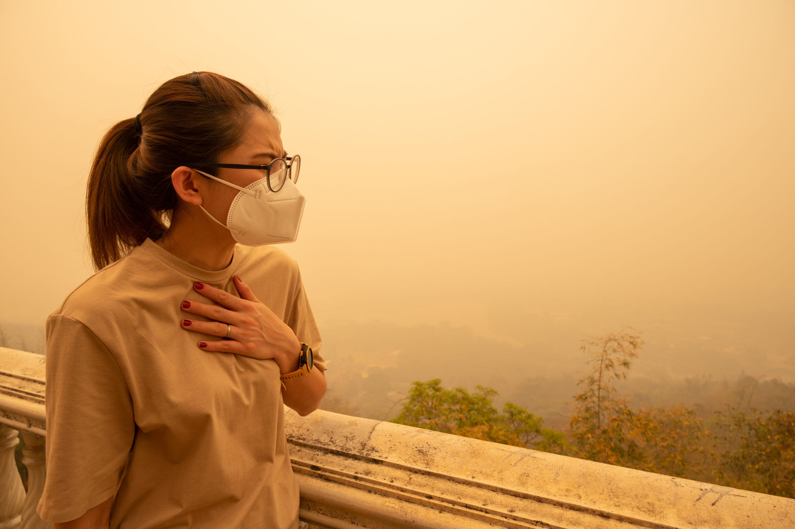 woman having trouble breathing from air pollution