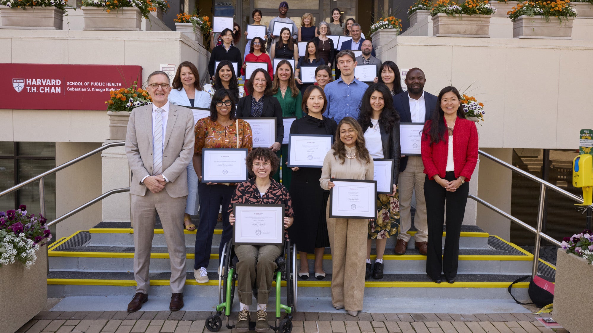 This year's award winners stand on the stairs in front of the Kresge building holding their certificates.