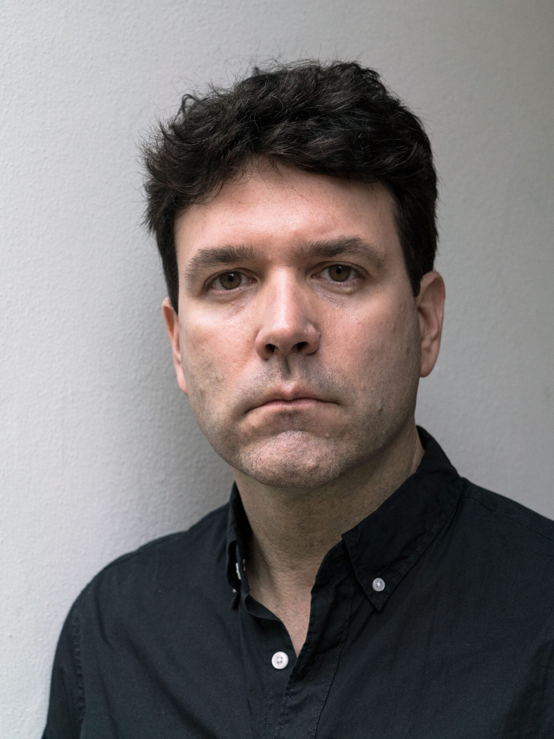 Jame Shea wearing a black, collared shirt.