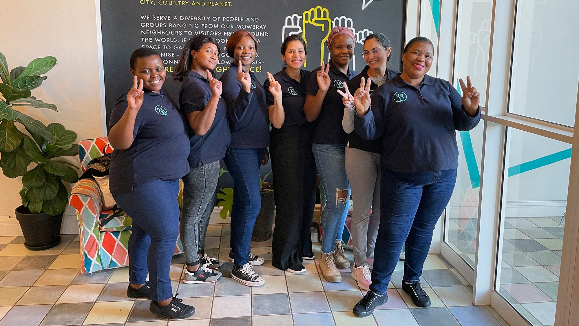 Seven women pose together with happy expressions.