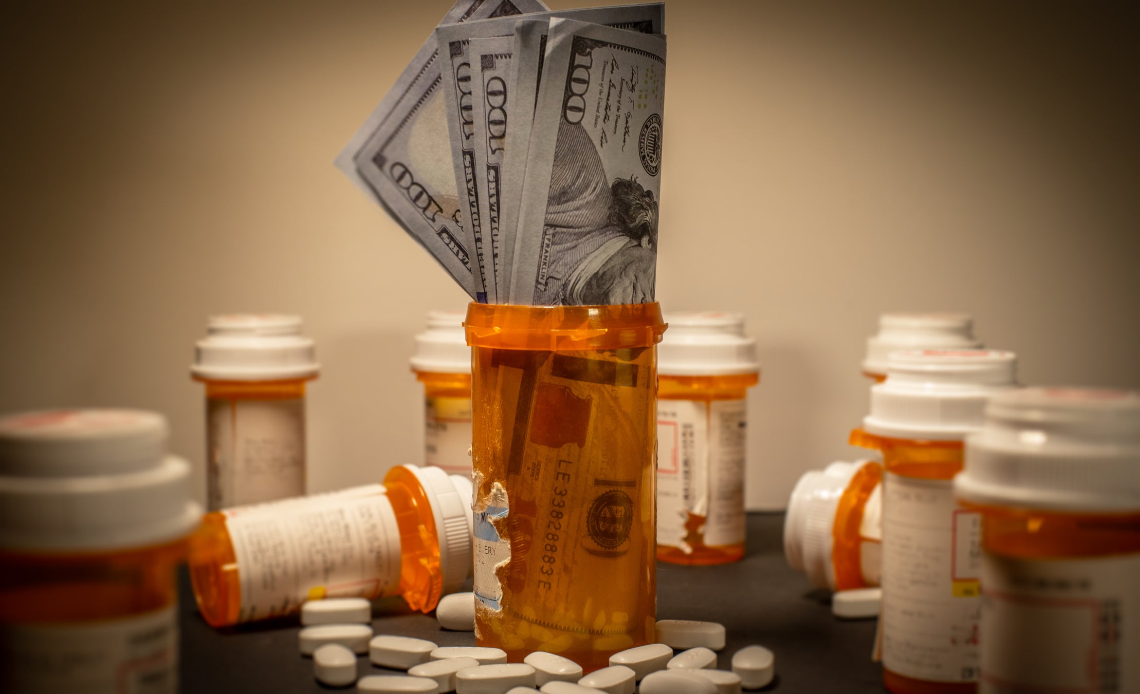 American $100 bills are stuffed into a prescription drug container.