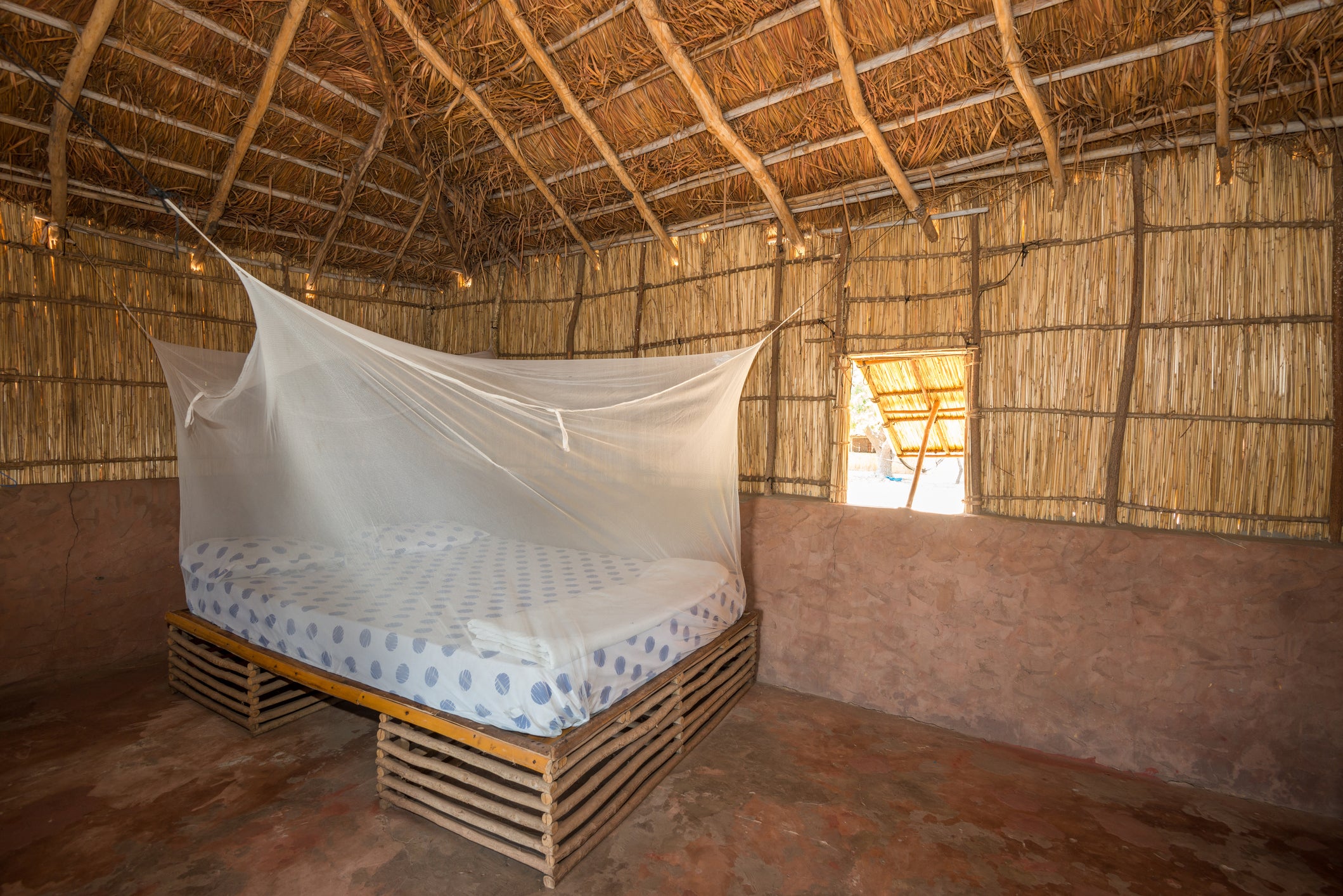 Bed with mosquito net in a hut in the Saloum Delta, Sine-Saloum, Senegal.