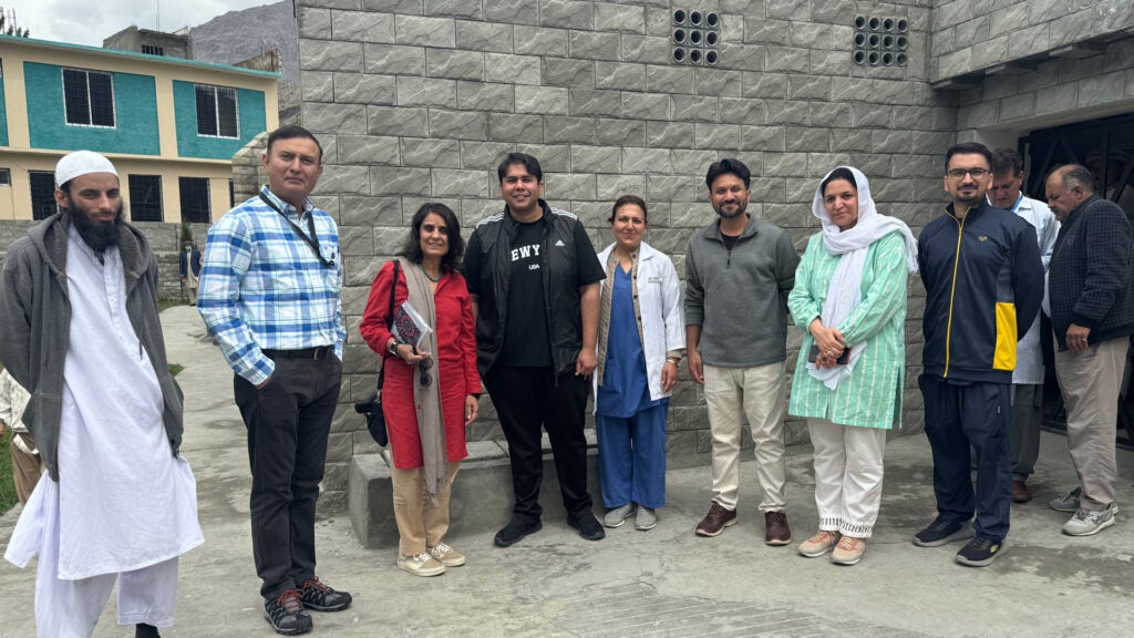 Salima Walani poses with colleagues outside a stone building.