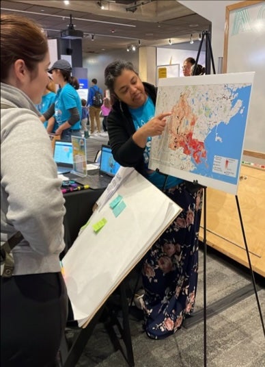 Amruta Nori-Sarma points to a map at a community engagement event