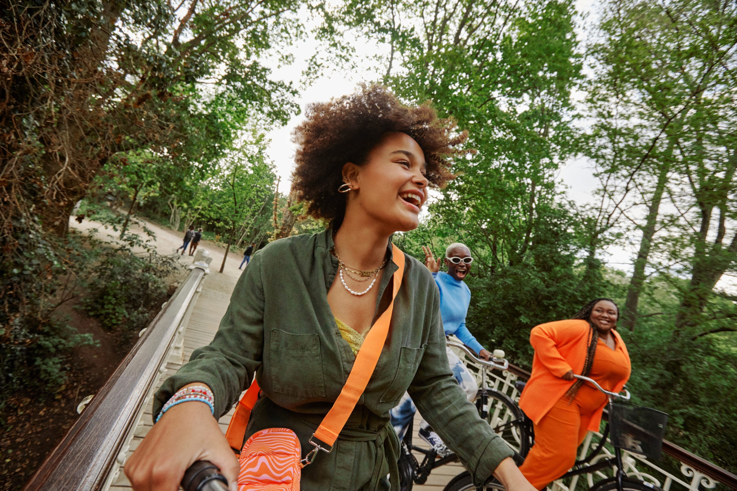 Happy female friends riding bicycles on bridge in park