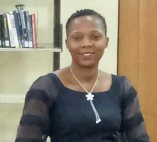 Photo of Oluwaseun Abiodun smiling in front of a bookshelf.