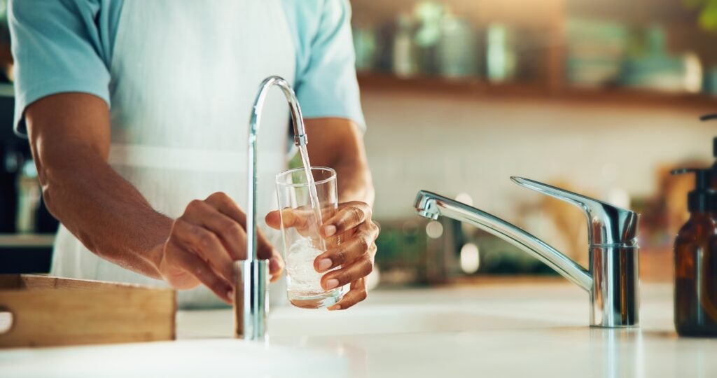 Man filling a cup of water from the faucet