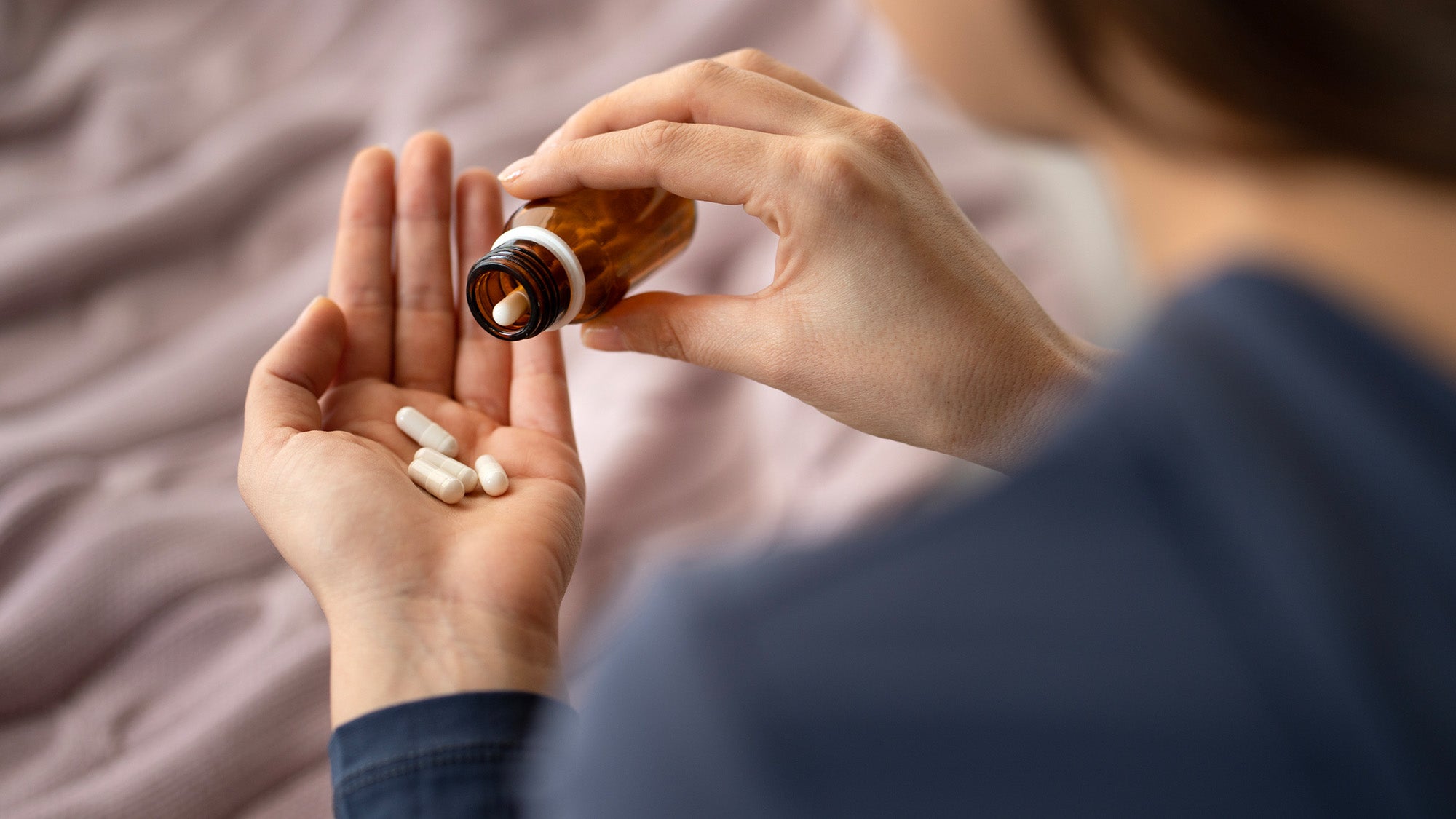 A person pours out pills from a bottle into their hand.