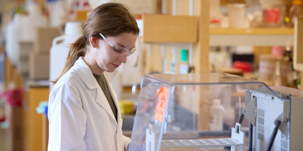 Female student in lab coat works next to a biosafe cabinet