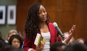 A forum audience member asking a question in front of a microphone.