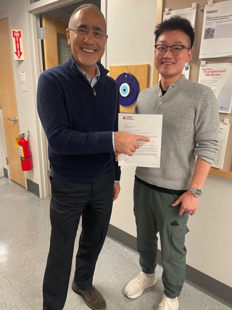Dr. Hotamisligil holds Dr. Zhe Cao's acceptance letter from ADA with research grant
