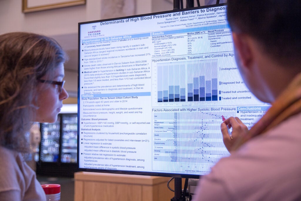 Two HSPH students review health care research data on a large monitor. 