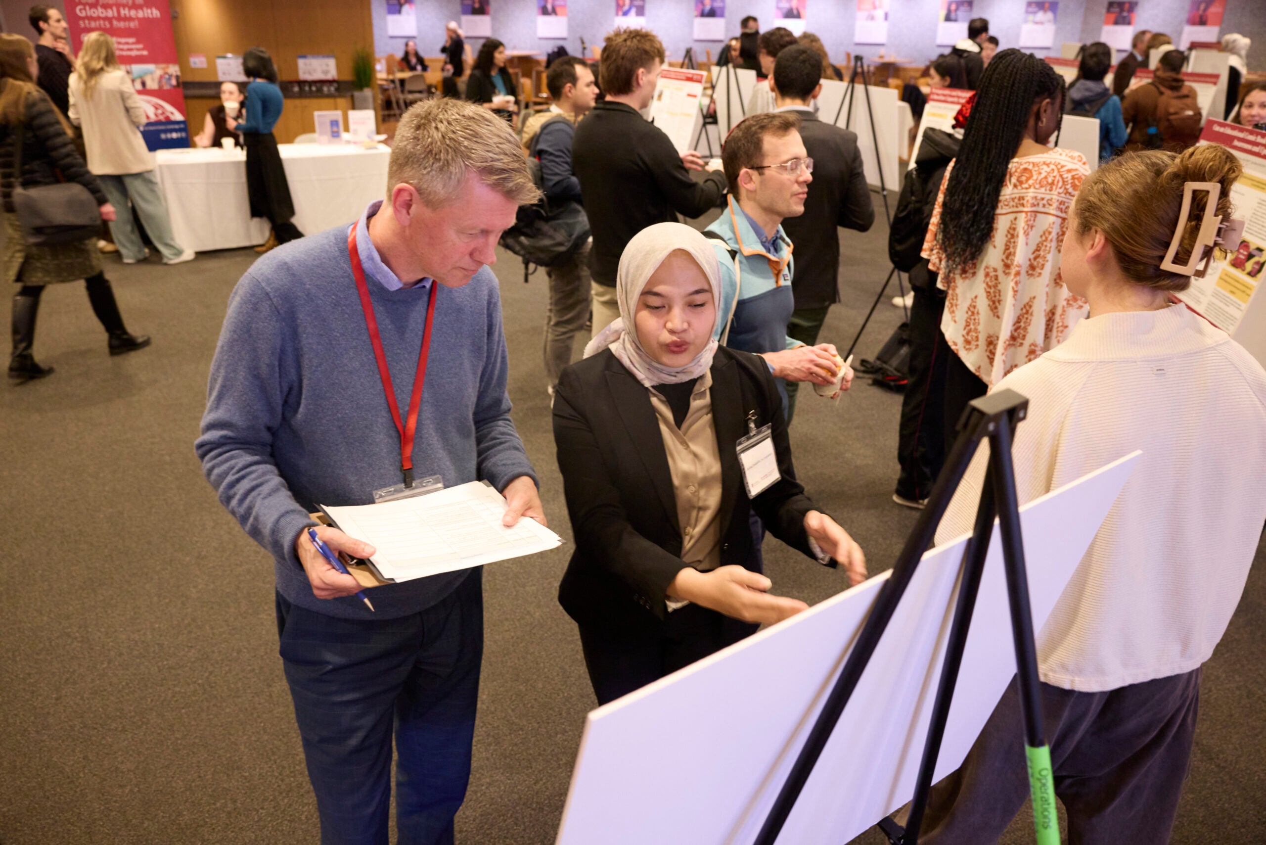 A student explains their research poster to professor Ole Norheim.