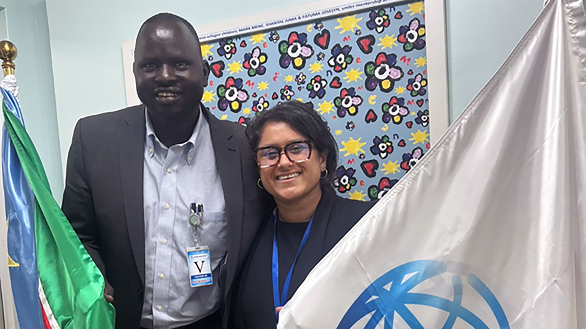 Deng Nyuon and Isha Nirola stand next to South Sudan and World Bank flags