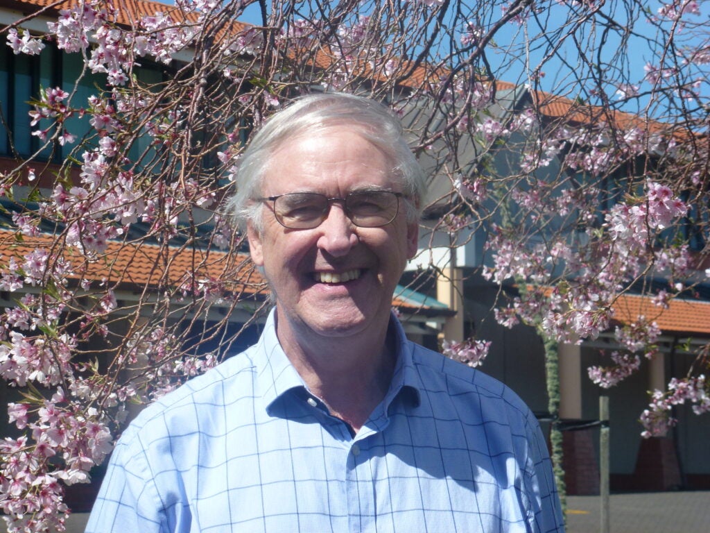Mark Elwood in front of a flowering tree.