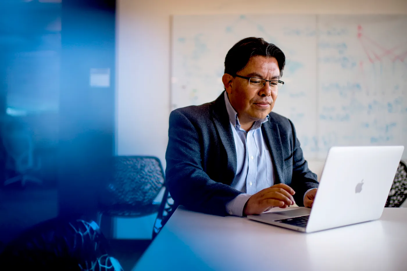 Mauricio Santillana seated at a desk typing on his laptop.