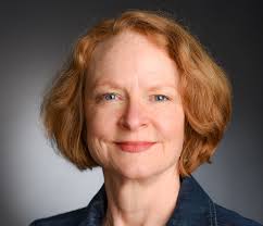 Headshot of women with short, light orange hair, gray background