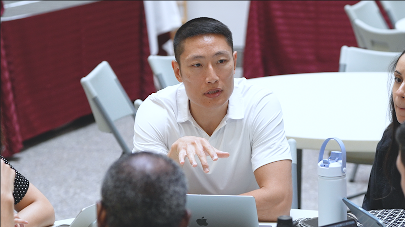 Sean Liu, wearing a white polo shirt, seated with other students