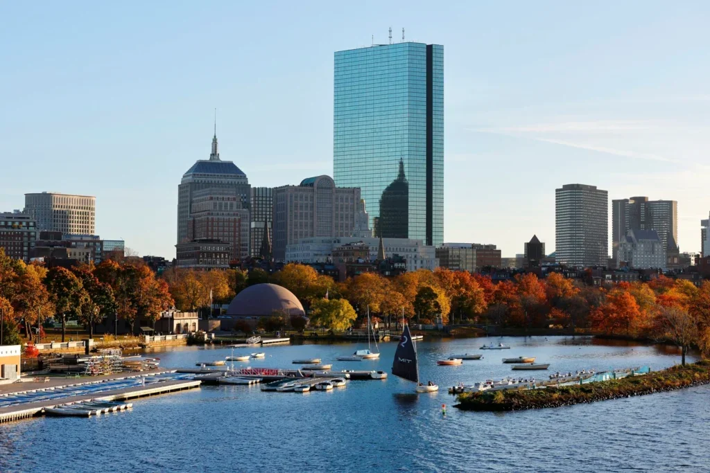 Boston skyline and harbor, skyscrapers, orange and red fall leaves, sailboat in the water