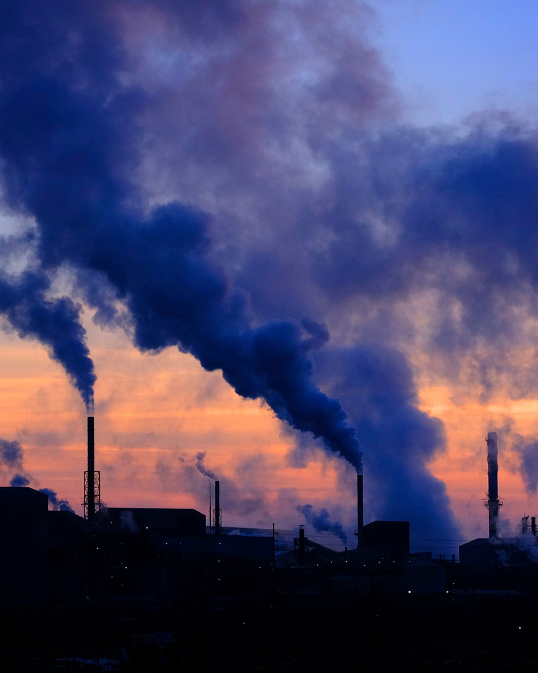 Pollution from factory smokestacks at sunset