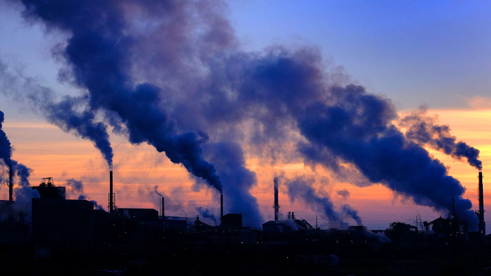 Pollution from factory smokestacks at sunset