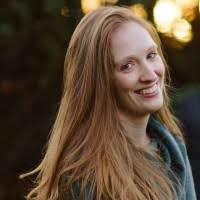 Headshot of woman with long light orange hair and tree in background