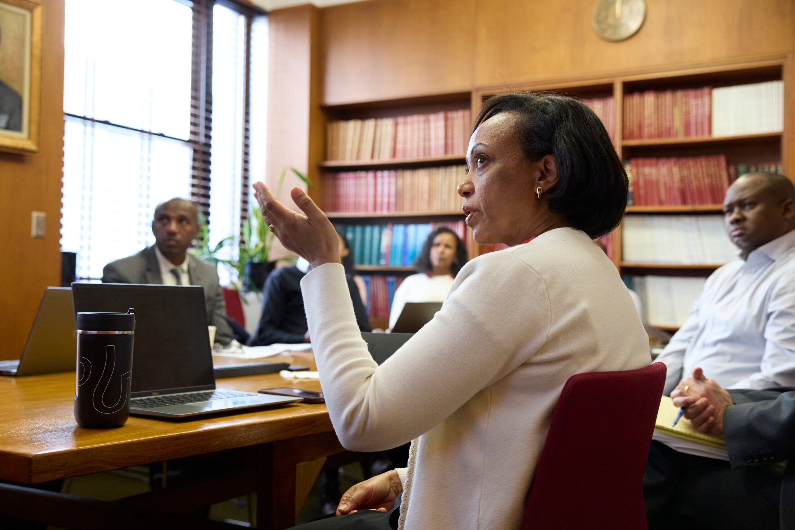 Lia Tadesse Gebremedhin gestures towards a presentation at a conference table.