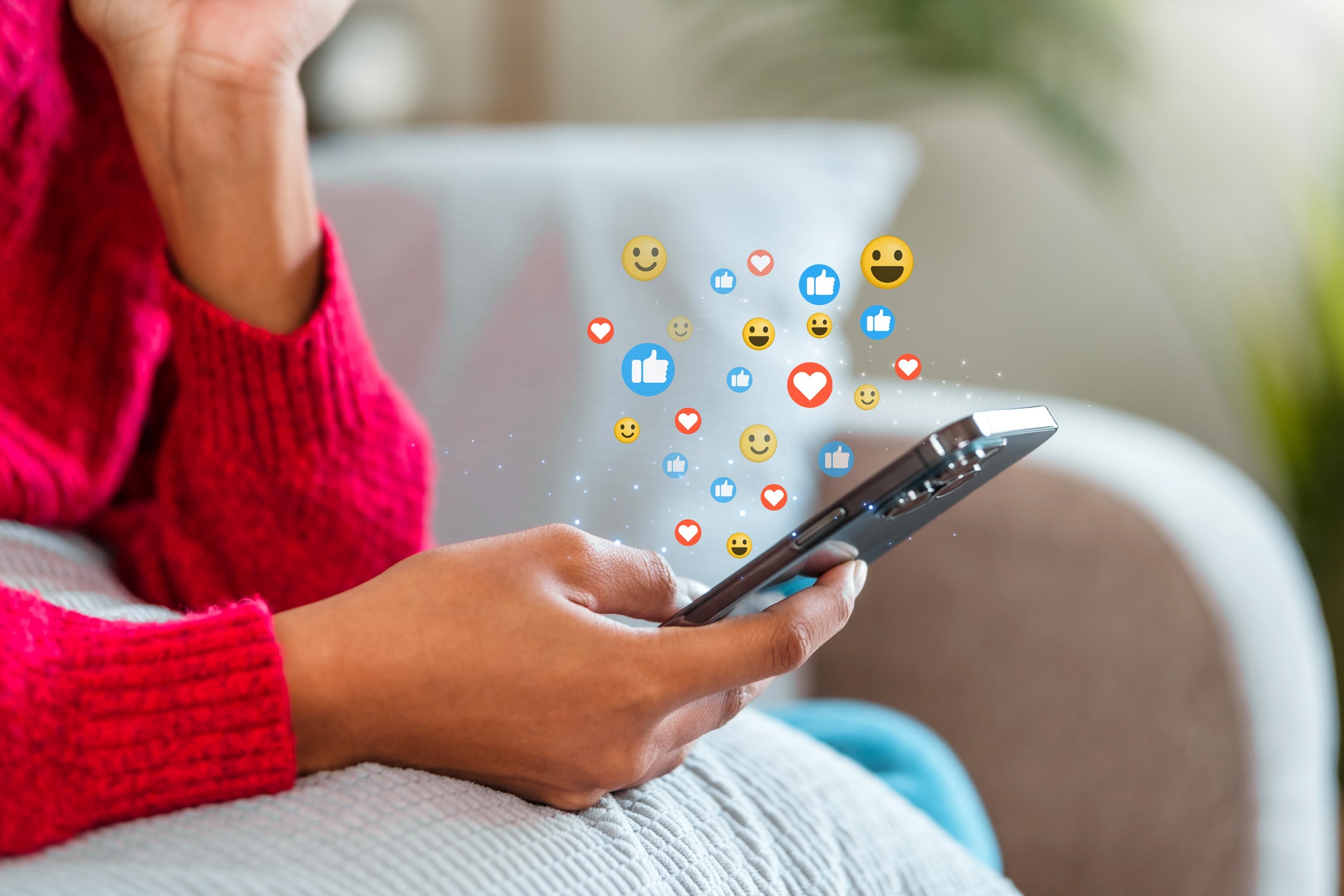 Hands holding a smart phone with social media react buttons floating above