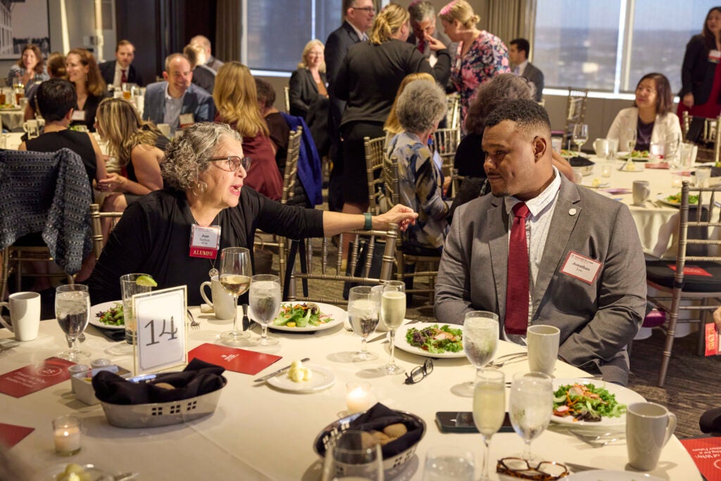 Alumni chat at a table. 