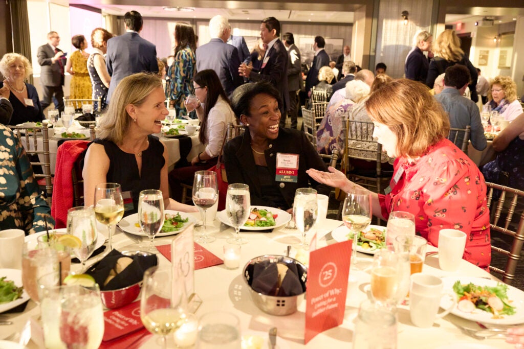 A group of three alumnae chat around a table. 