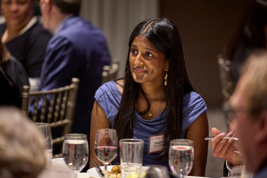 An alumna looks attentively to a tablemate out of frame. 