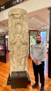 Alan Hernandez Gutierrez stands next to a museum statue
