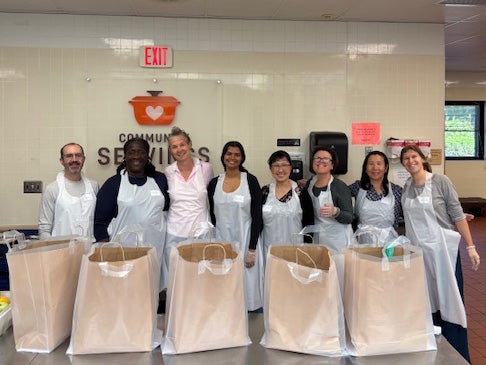 Volunteers pose before bags of donated meals at Community Servings.